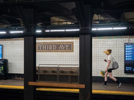 A man walking with flowers at Third Ave subway station, New York City.
