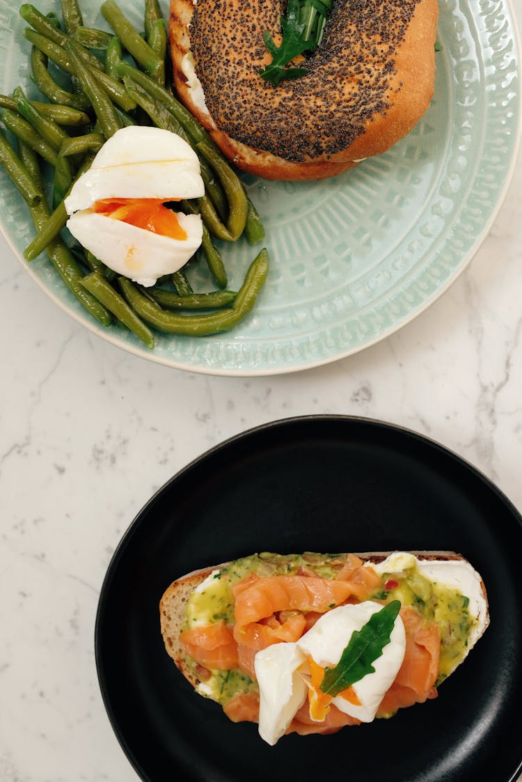 Plates With Tasty Bagel And Toast With Boiled Eggs And Asparagus On Table