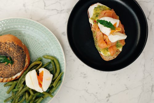 Free Tasty lunch with bagel and toast with poached eggs served on plates Stock Photo