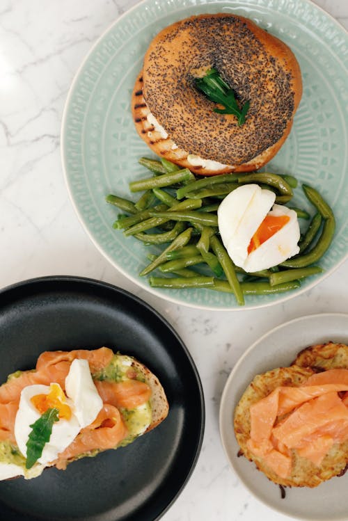 Free Plates with bagel with asparagus and boiled egg and toasts with fish served on table Stock Photo