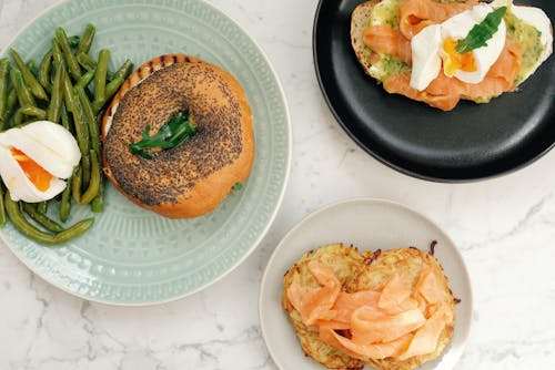 Free Top view of tasty bagel with asparagus and poached egg and toasts with fish served on white marble table in modern kitchen at home Stock Photo