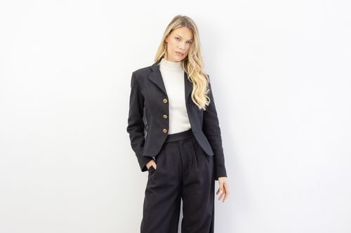 Free Elegant woman poses in a sophisticated black suit against a white background. Stock Photo
