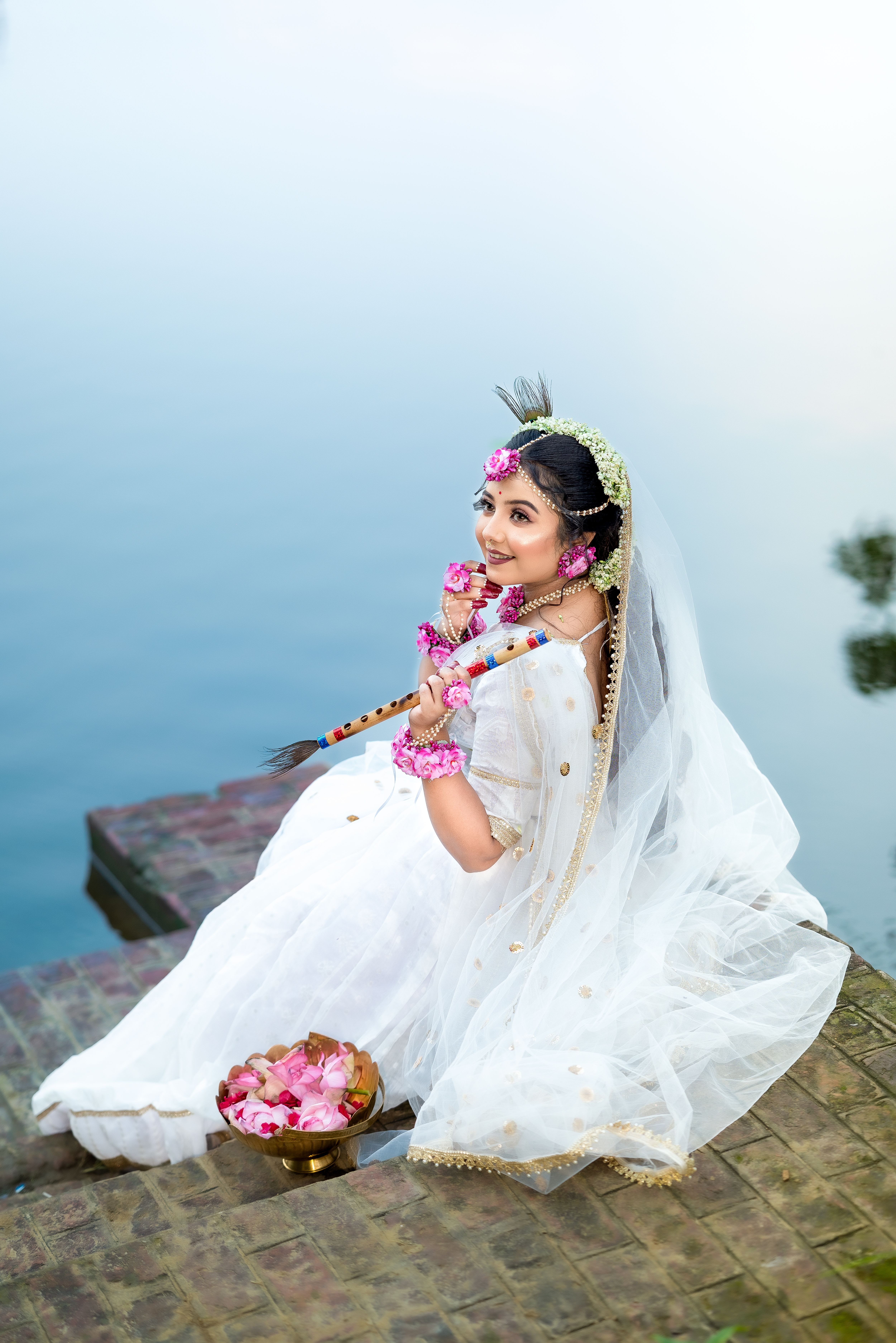 Woman in Traditional Attire Holding a Flute by the Water · Free Stock Photo
