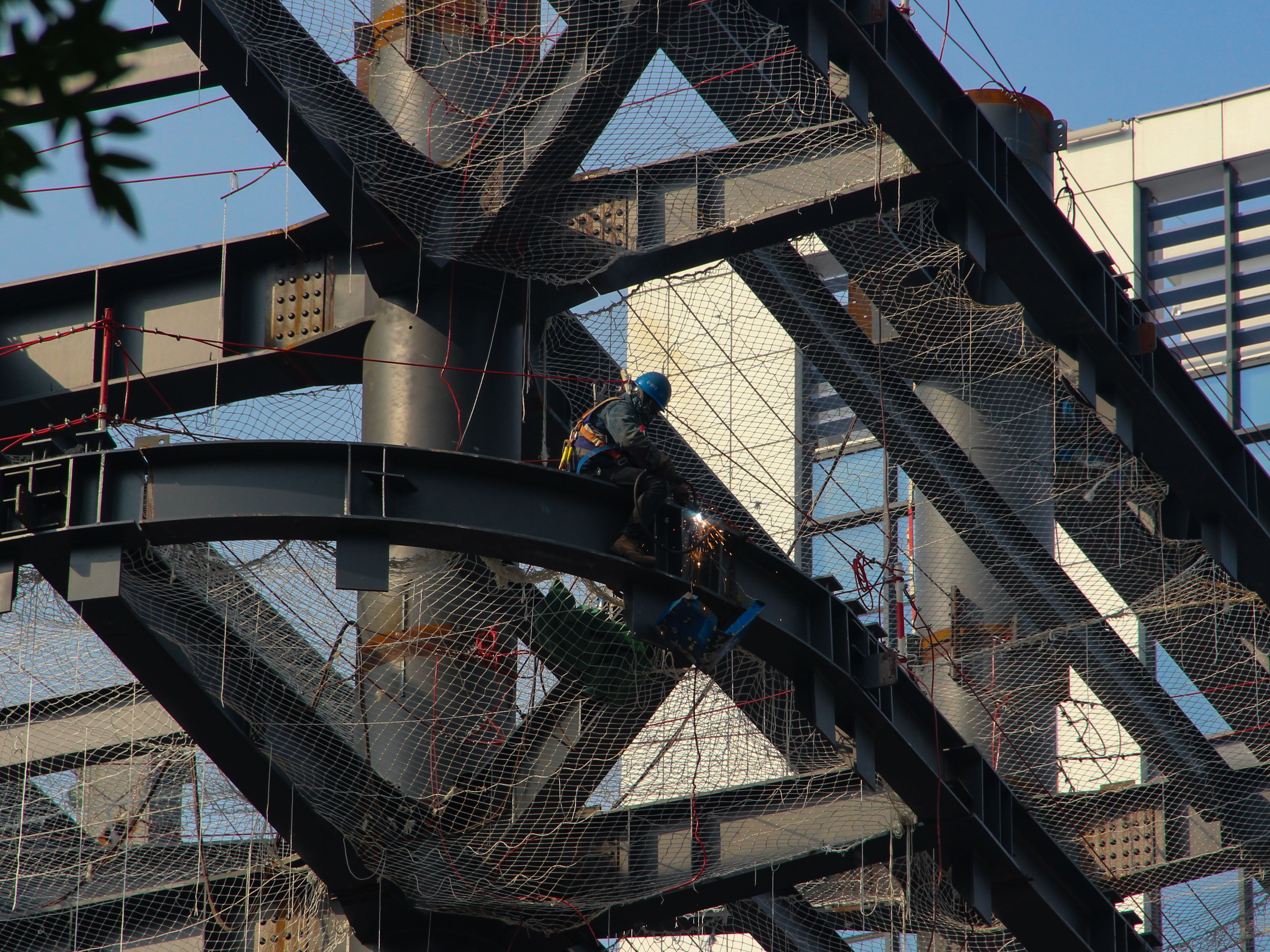 Construction worker welding on a steel structure while wearing full safety equipment