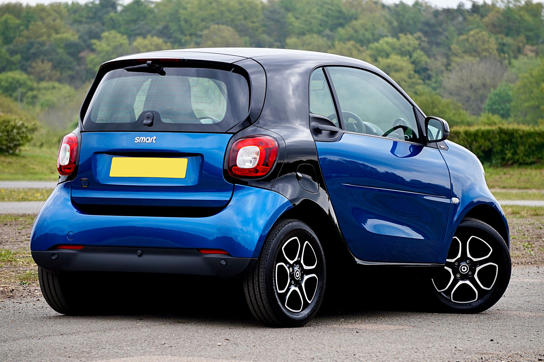 A blue Smart car parked in a scenic outdoor setting, showcasing modern design and compact size.