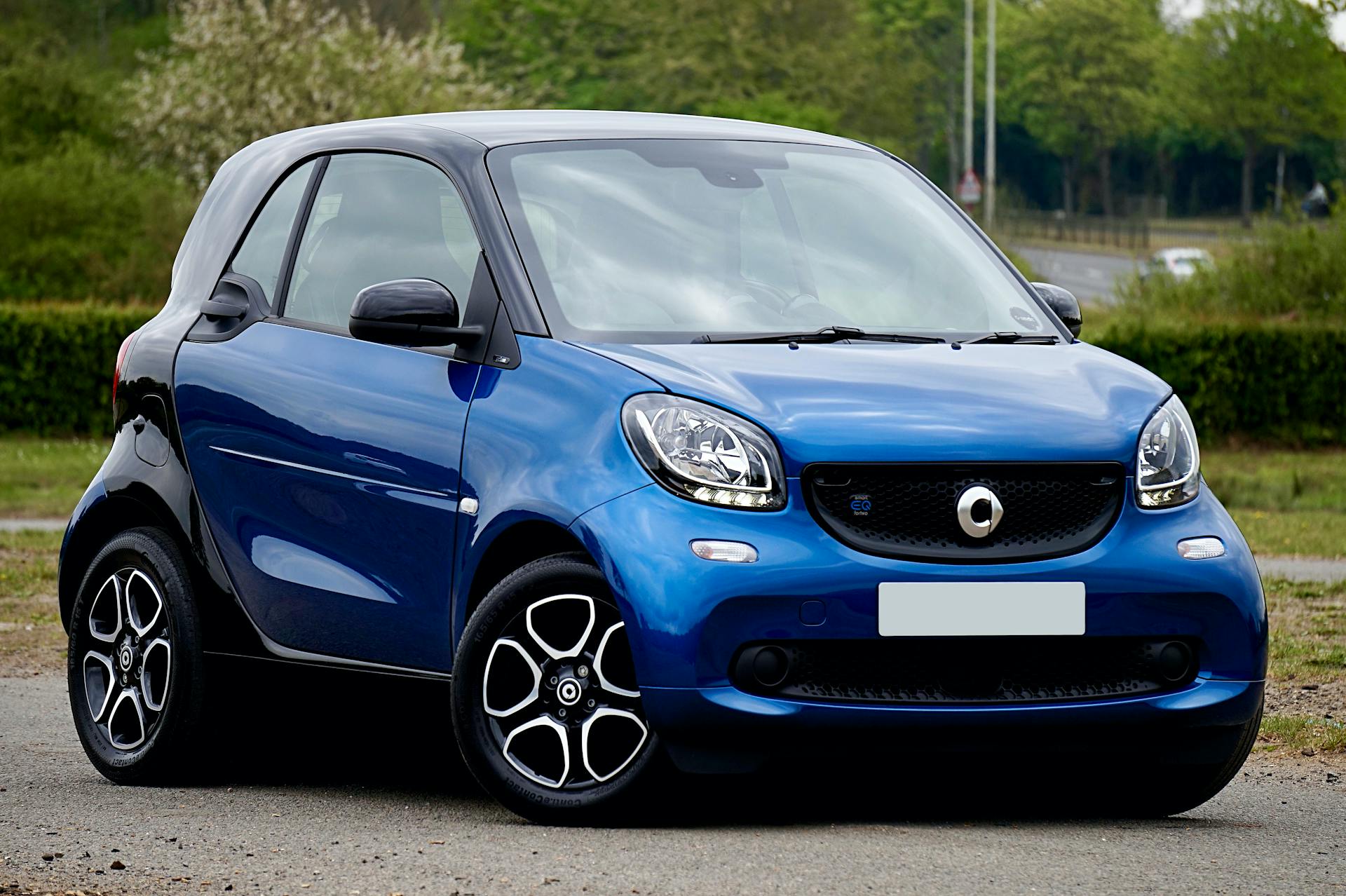 A shiny blue electric car parked outdoors on a pleasant day in the UK.