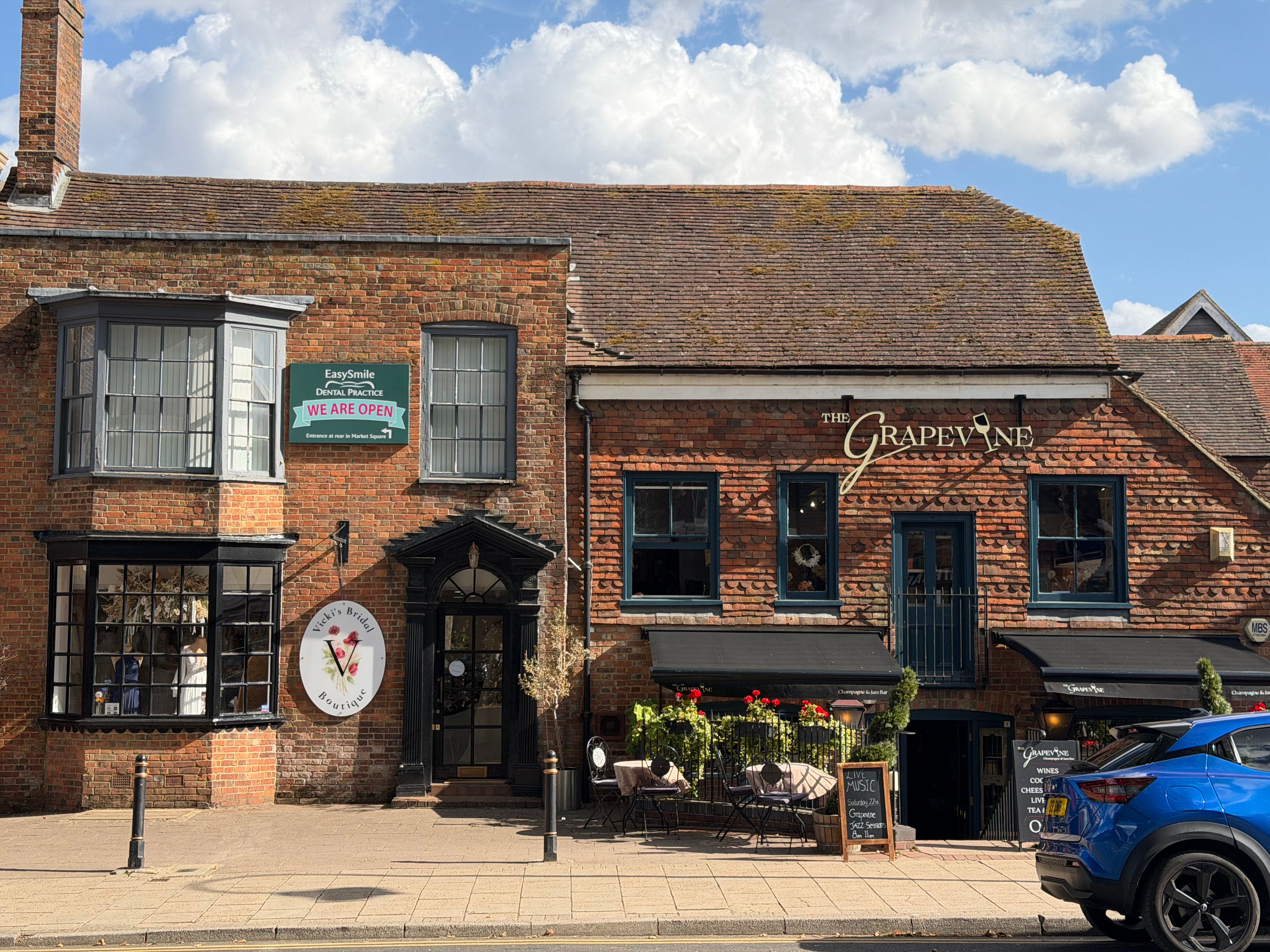A quaint street view of a brick building housing a cafe and dental practice in Tenterden, England.