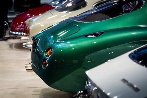 Free Captivating side view of vintage sports cars lined up at an indoor auto show, highlighting their sleek designs. Stock Photo