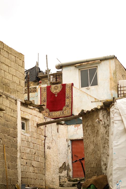 Free Rustic Moroccan buildings with a vibrant red rug drying outside, showcasing cultural charm. Stock Photo
