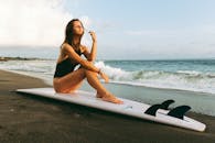 一名女子坐在海边的冲浪板上，享受着宁静的海滩一天