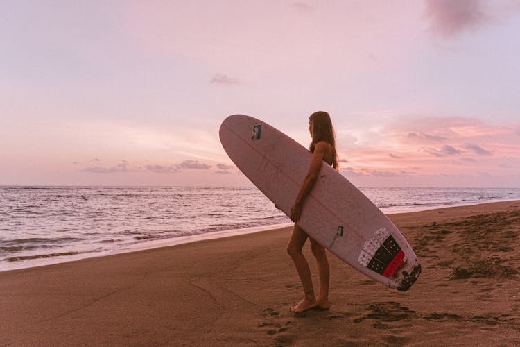 Woman Carrying Surfboard At The Beach