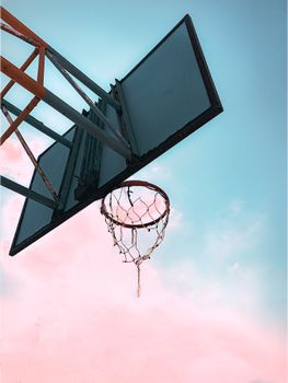 From below of basketball backboard with hoop placed on sports ground against colorful sky