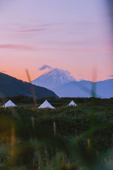 日出时分，堪察加半岛的露营地风景如画，帐篷背后是连绵的山脉