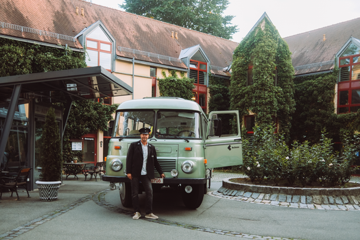 A vintage bus with a driver parked in the scenic courtyard of Schlosshotel Althörnitz, Germany.