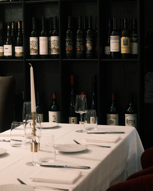 Free Cozy dining setup in a restaurant with a wine collection backdrop, perfect for intimate gatherings. Stock Photo