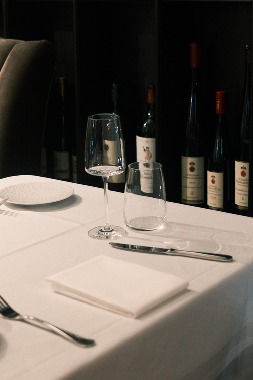 Free Sophisticated table setting in a German restaurant with wine bottles in background. Stock Photo