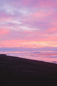 A breathtaking pink sky at sunset over a beach in Kamchatka, Russia, capturing serene waves and a cinematic nature.