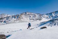 徒步旅行者独自在清澈的蓝天下，用徒步旅行杆探索白雪覆盖的山脉