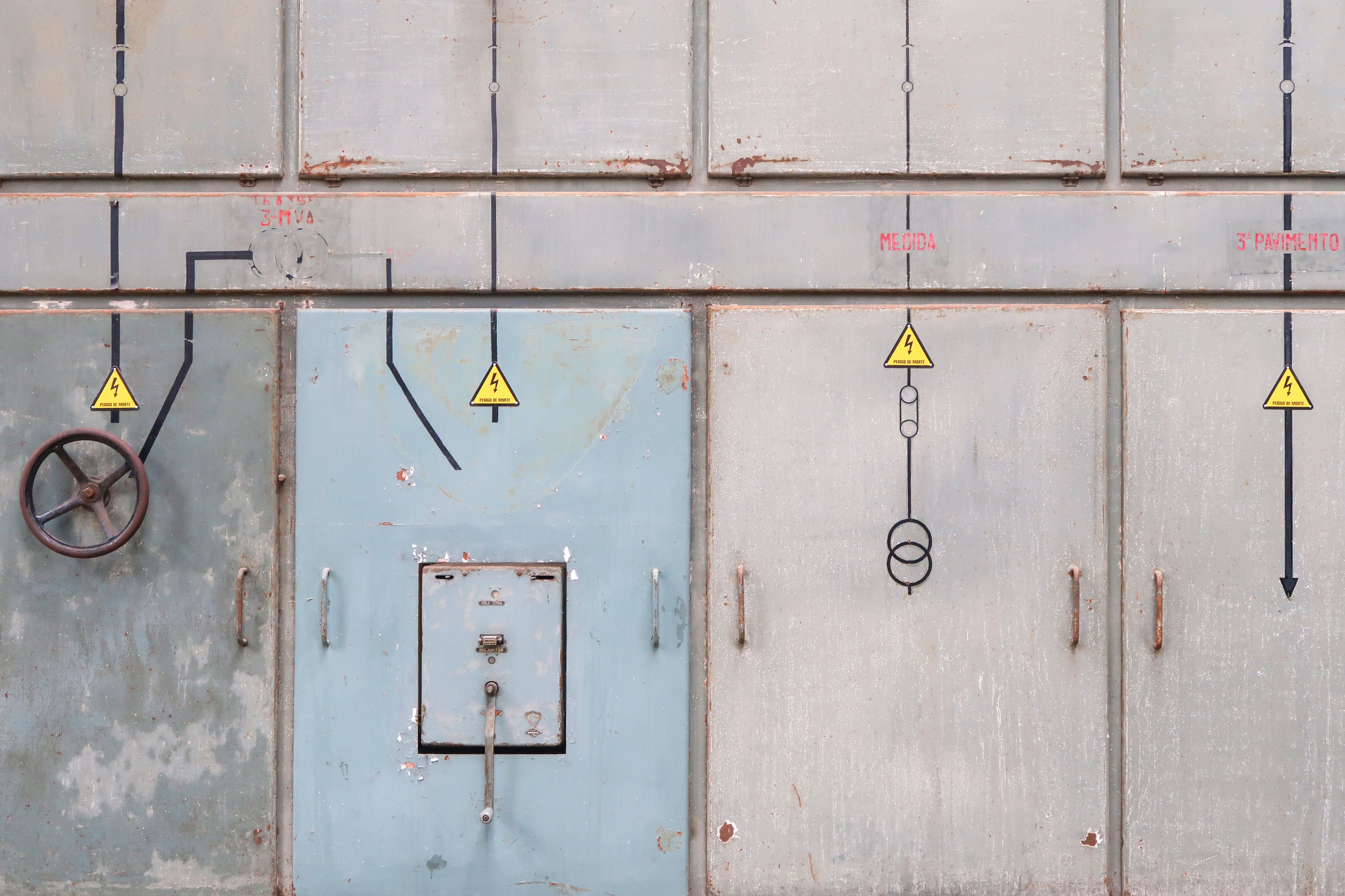 Weathered industrial control panel with warning signs and levers.