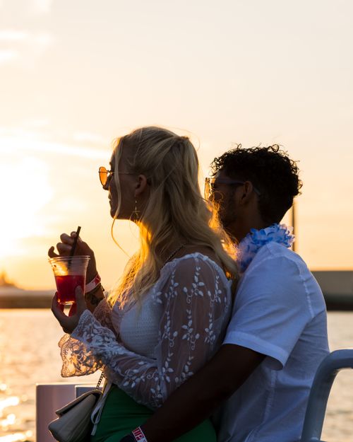 Free Romantic sunset moment at Rotterdam harbor with a couple embracing, enjoying a drink. Stock Photo