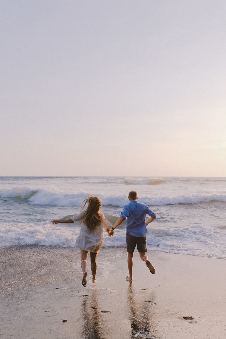 Couple Running Together On The Beach