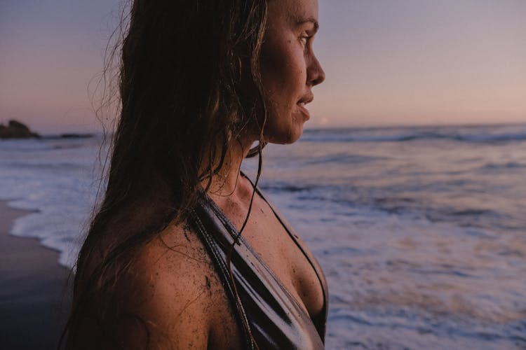 Woman Standing On Shore During Sunset