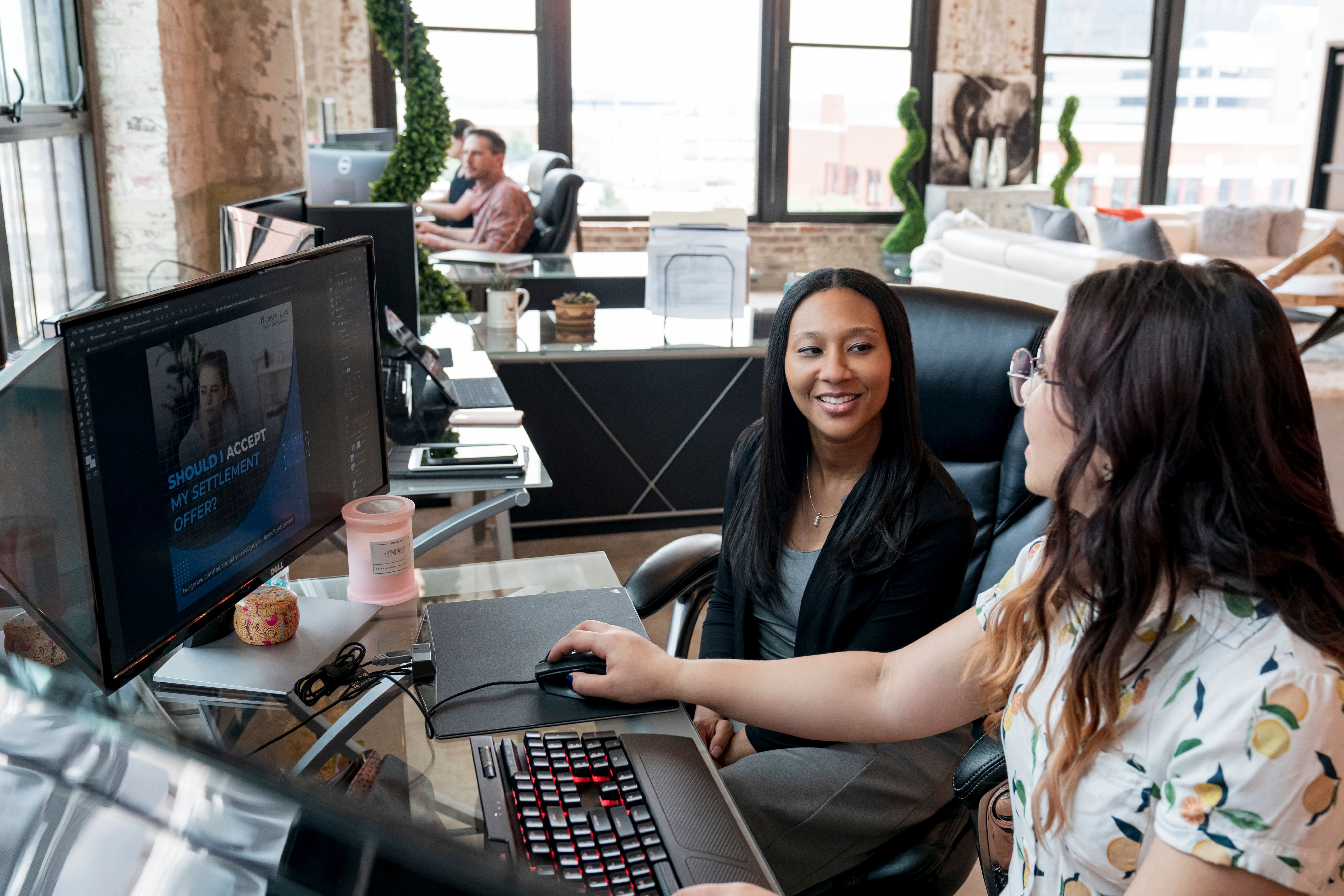 Two women collaborating at a computer in a modern office setting, St. Louis.