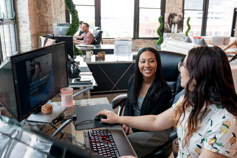 Two women collaborating at a computer in a modern office setting, St. Louis.