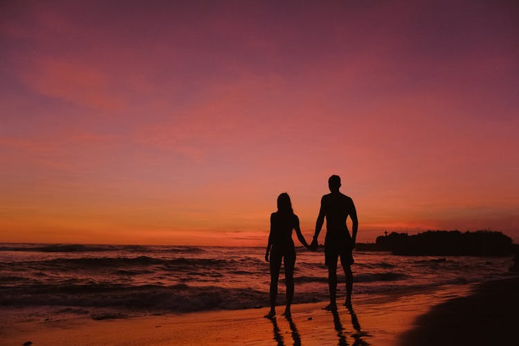 Silhouette Of A Couple Standing On Shore Together