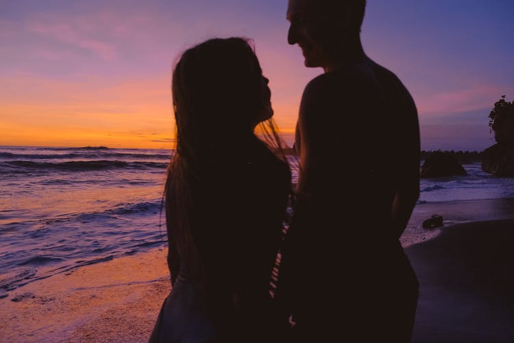 Man And A Woman At The Beach At Sunset