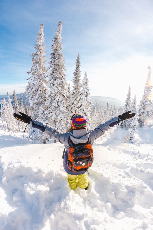 Free Person with arms outstretched enjoying a snowy mountain view, symbolizing freedom and adventure. Stock Photo