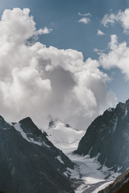 Free Stunning view of snow-capped mountains and dramatic clouds in a scenic landscape. Stock Photo