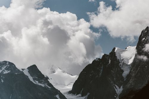 Free Stunning landscape of snow-covered mountains with a blue sky and floating clouds. Stock Photo