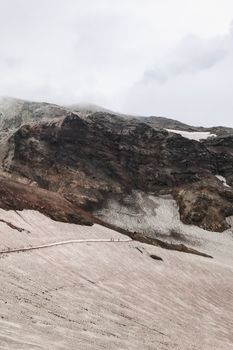 从空中俯瞰，山脉崎岖，天空多云，山坡上覆盖着积雪