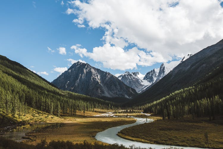 River Between Grass Near Mountains