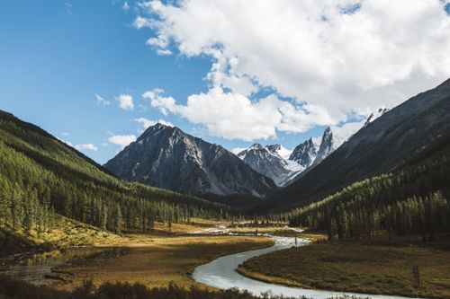 Free Beautiful mountain view with a winding river, forest, and blue sky. Stock Photo