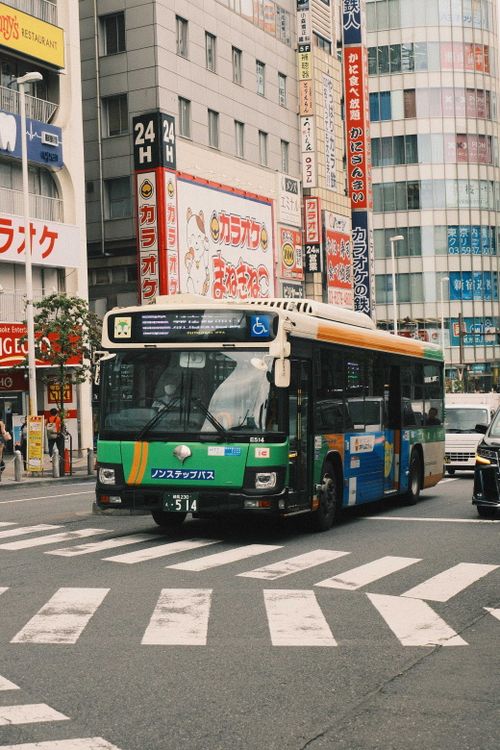 Free Urban scene featuring a colorful city bus navigating a bustling Tokyo street. Stock Photo