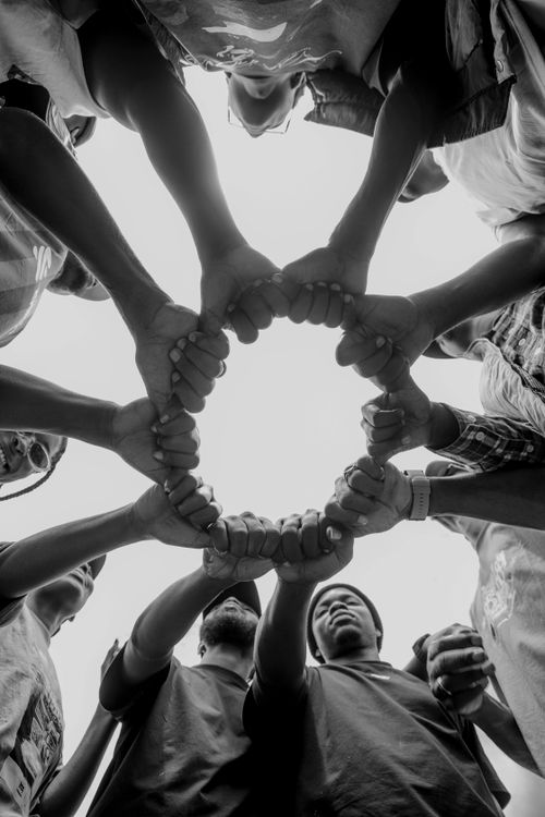 Free A group of diverse individuals join hands forming a circle symbolizing unity and teamwork. Stock Photo