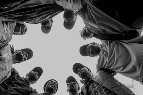 Free Black and white photo depicting a diverse group of adults in a circular formation, viewed from below, fostering unity. Stock Photo