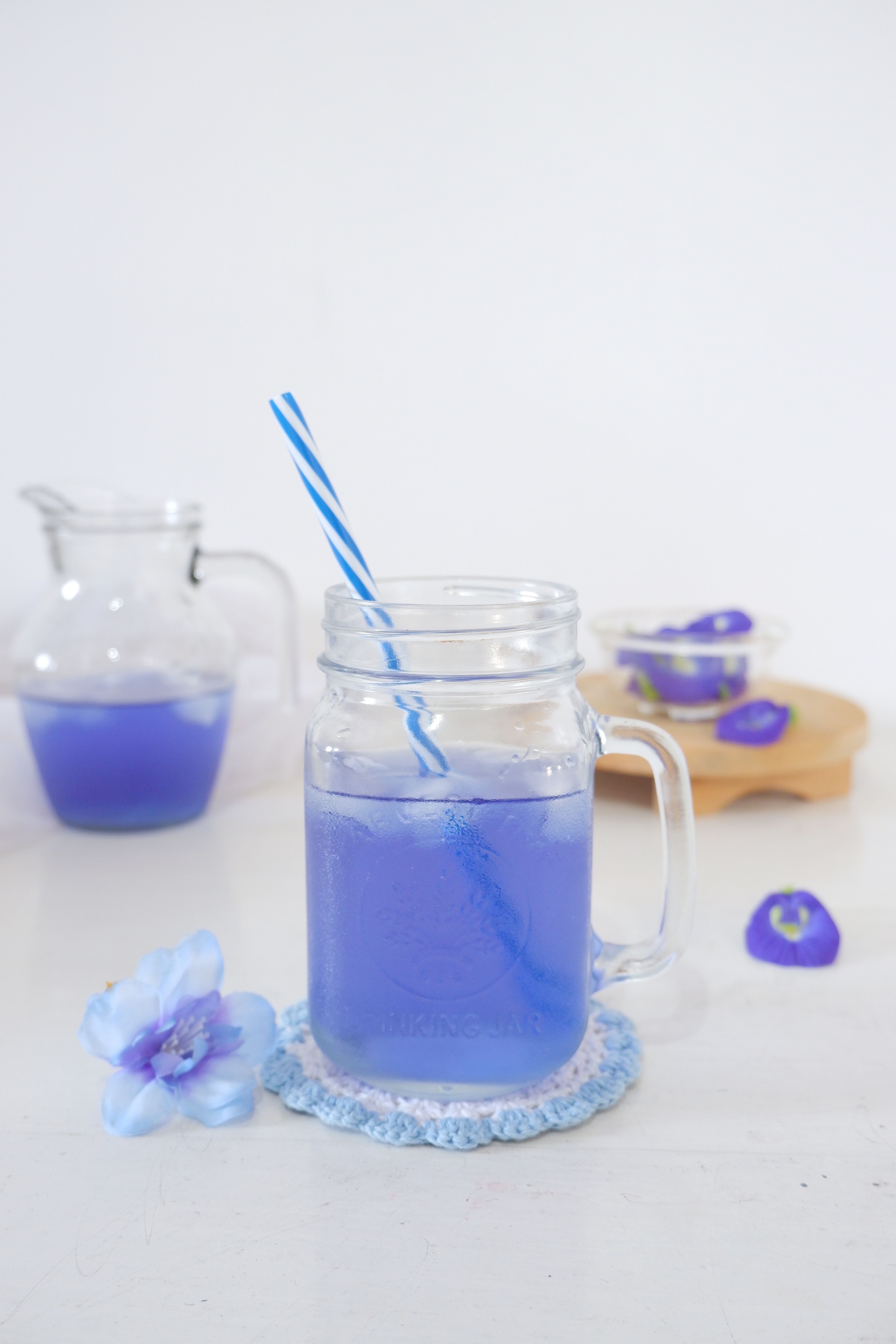 Vibrant blue butterfly pea flower iced beverage in a jar with ice and a straw