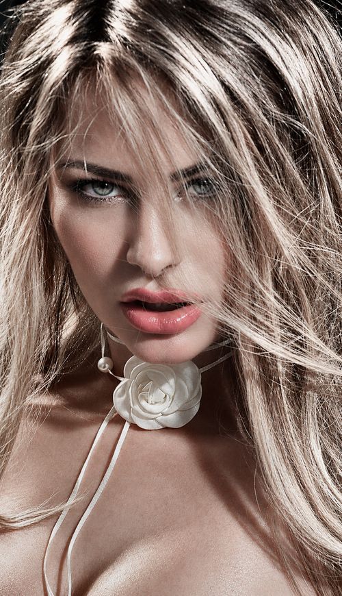 Free Detailed close-up of a woman with a floral necklace, vibrant eyes, and elegant hair. Stock Photo
