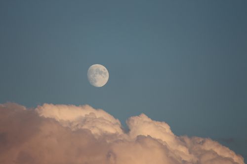 Free A serene full moon rises above fluffy clouds in the evening sky. Stock Photo