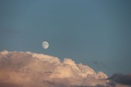 Free Tranquil image of the moon above colorful clouds on a clear evening sky. Stock Photo