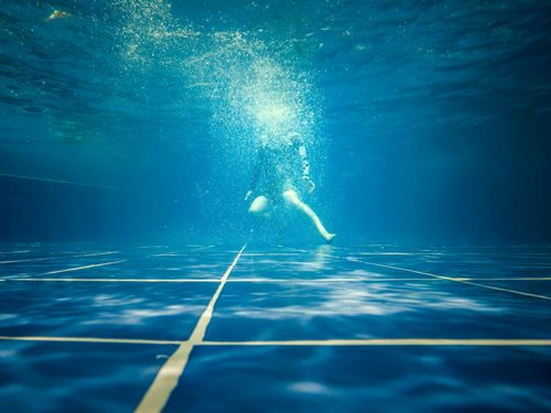 Free Dramatic underwater shot of a swimmer surrounded by bubbles in a clear swimming pool. Stock Photo