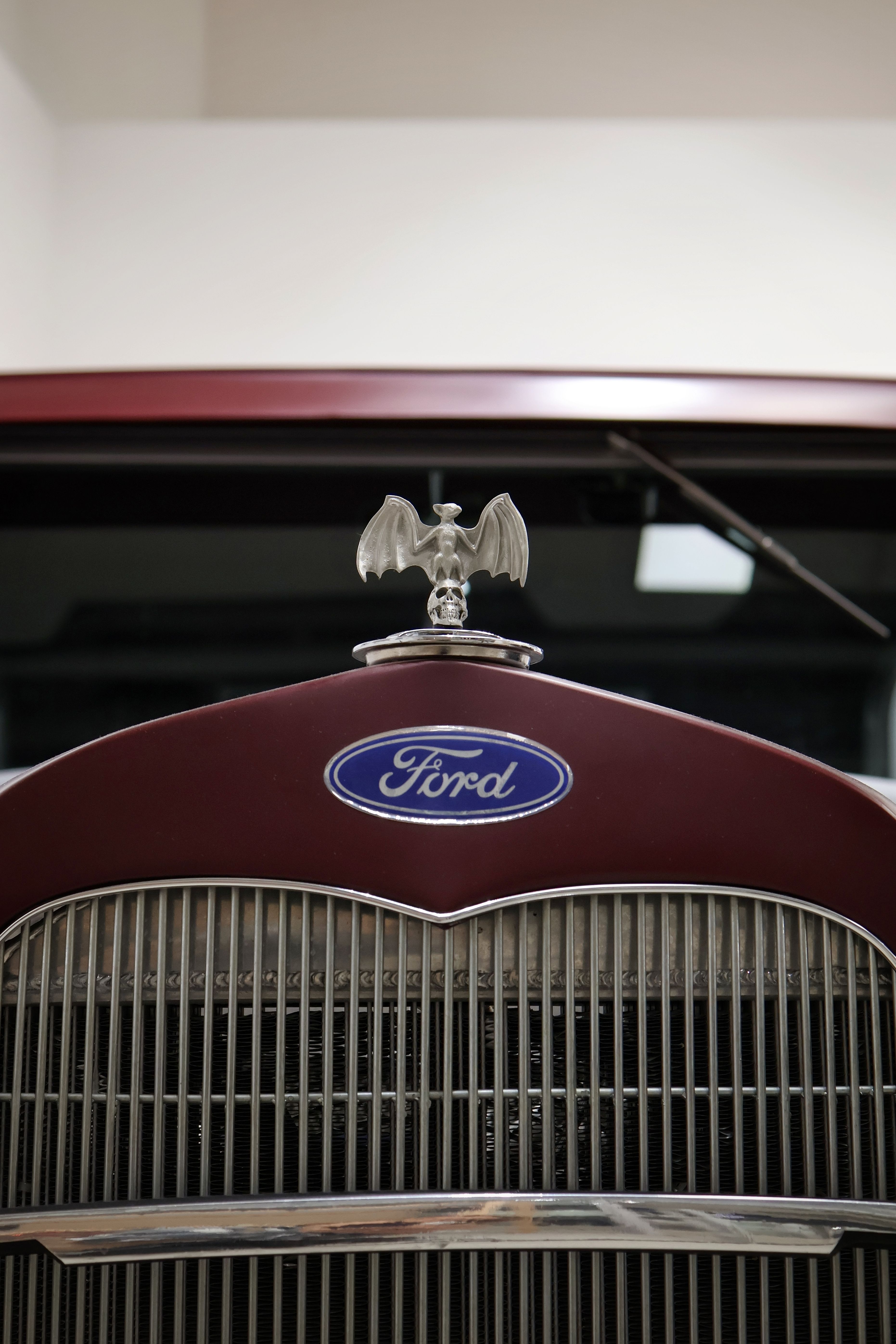 Fotomural Primer plano de la parrilla de un Ford clásico con un distintivo adorno en el capó, en un ambiente interior.
