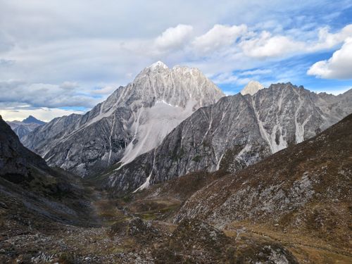 Free Dramatic landscape of towering jagged mountains under cloudy blue sky. Stock Photo