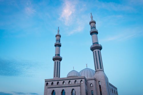 Free Elegant mosque minaret and dome against a clear blue sky during the day, symbolizing peace and spirituality. Stock Photo