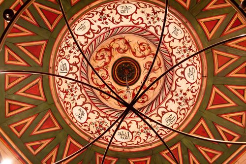 Free Artistic view of a decorative dome ceiling featuring geometric patterns and Arabic calligraphy. Stock Photo