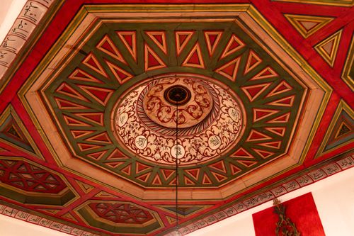 Free A vibrant, ornate ceiling with Islamic geometric patterns and calligraphy in red and green hues. Stock Photo