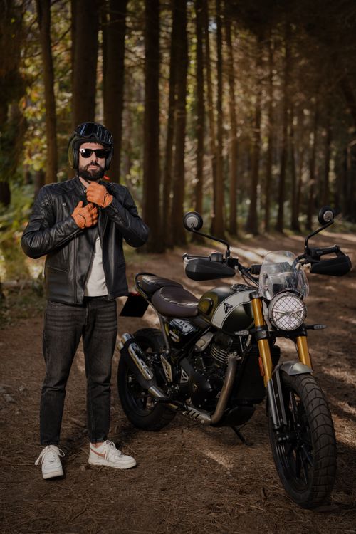 Free Male biker with motorcycle in a scenic forest, exuding adventure and confidence. Stock Photo